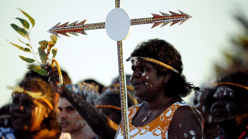 An Aboriginal woman holds a cross prior to a mass at Barangaroo in Sydney.