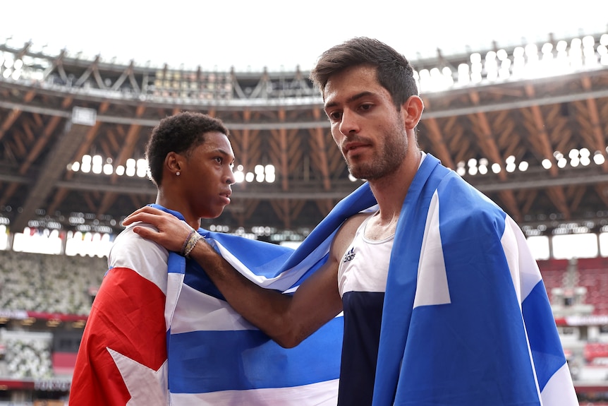 A man with his hand placed on another man shoulder after beating him in long jump at the Olympics