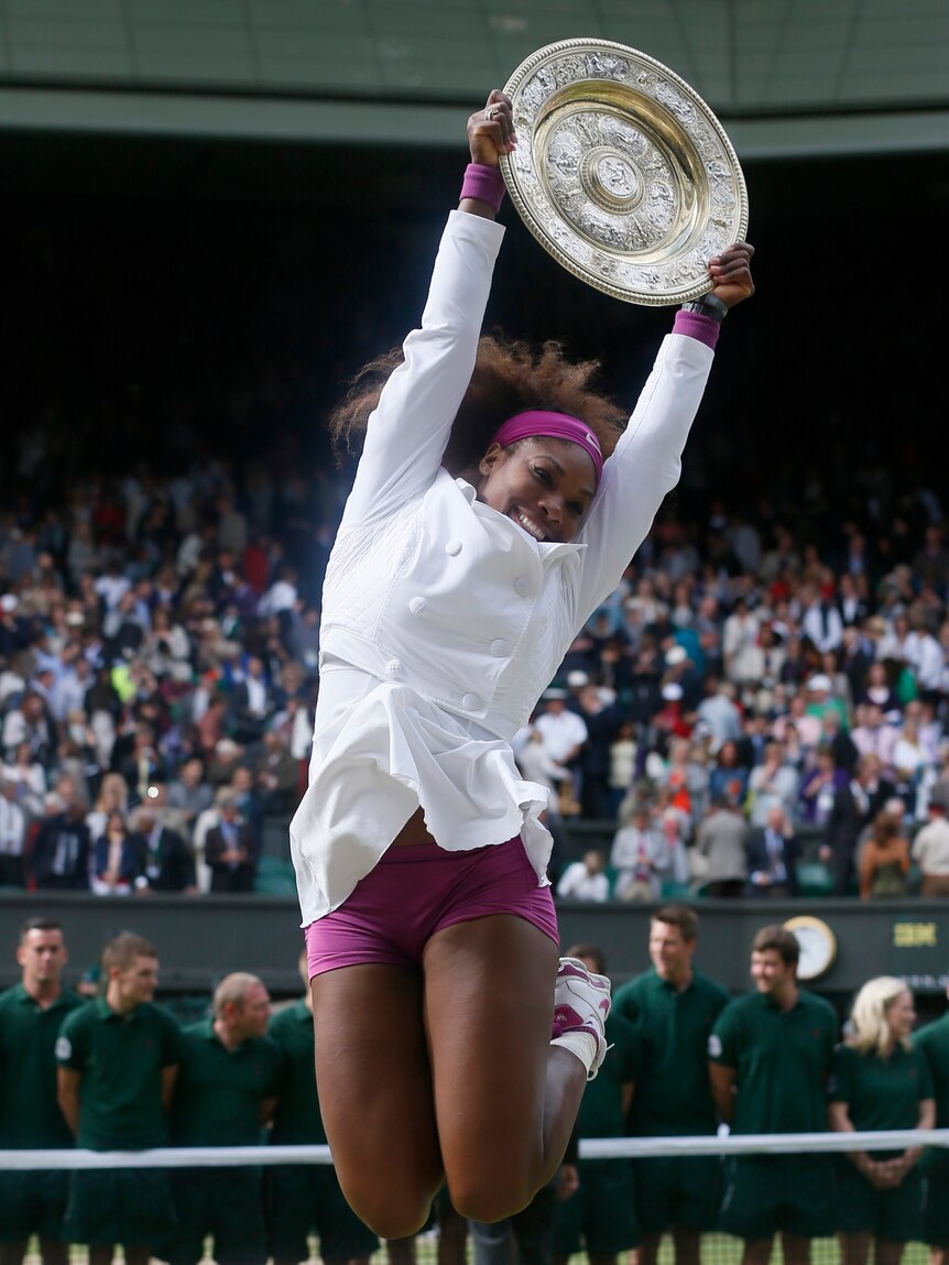 Serena Williams jumps with her trophy after defeating Agnieszka Radwanska in their women's final tennis match at Wimbledon