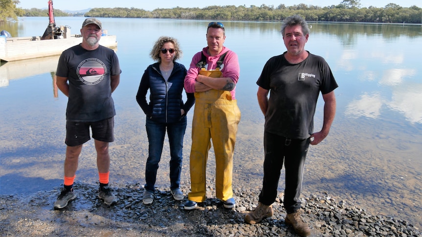 Four oyster growers standing together at the egde of the Nambucca River.