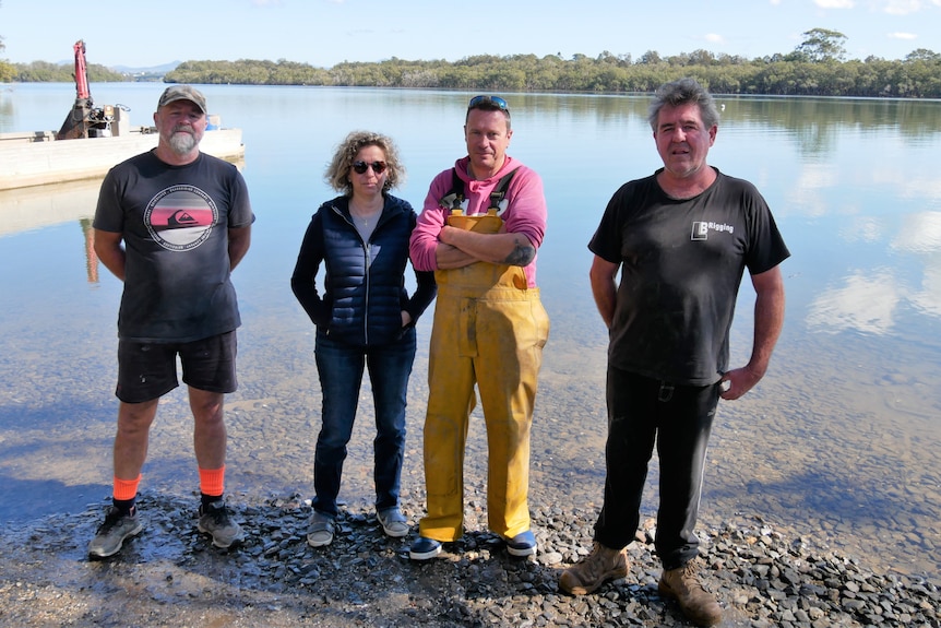 Four oyster growers standing together at the egde of the Nambucca River.