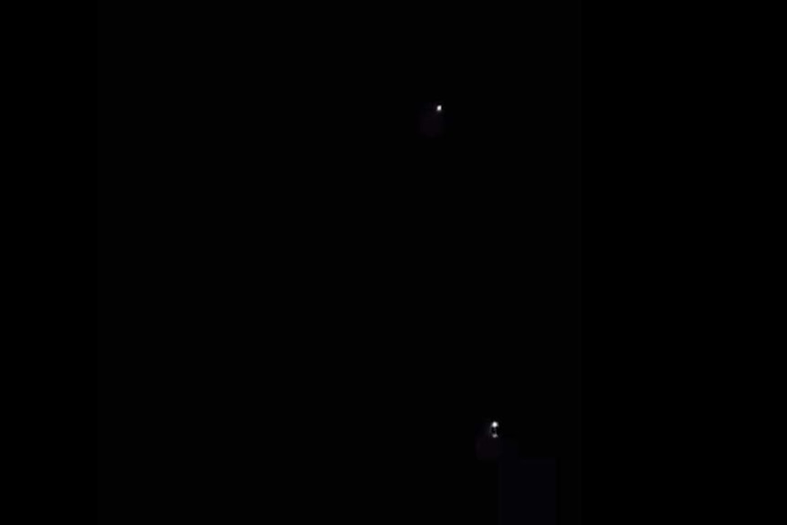 two larger lights with smaller light in black sky
