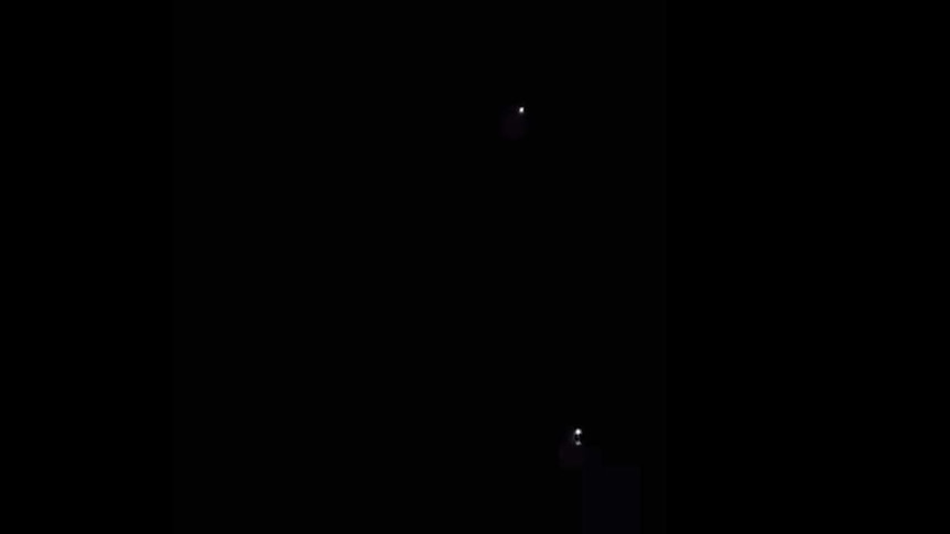 two larger lights with smaller light in black sky