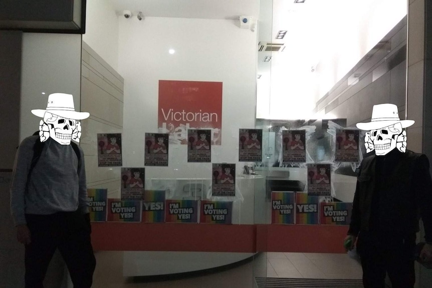 Homophobic posters glued to the window of the Victorian ALP headquarters, with two members of Antipodean Resistance.