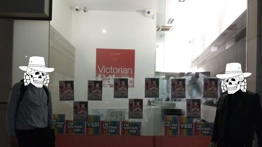 Homophobic posters glued to the window of the Victorian ALP headquarters, with two members of Antipodean Resistance.