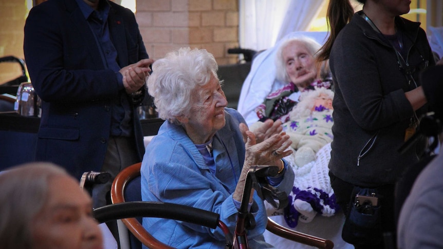 A lady dancing, surrounded by other residents