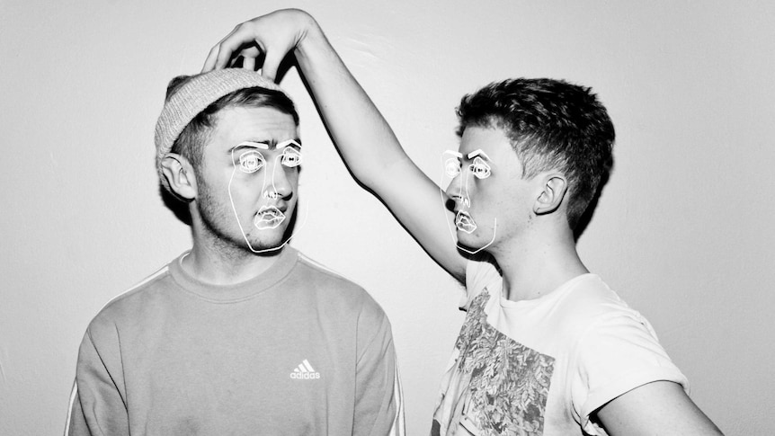 One of the members of Disclosure grasps the other's head with his hand, with white drawn faces superimposed over the duo.