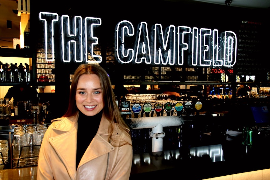 A woman wearing a leather jacket stands in front of the bar of the Camfield in Burswood, in Perth's east.