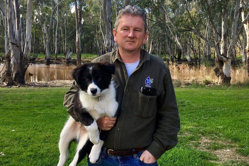 Farmer Jamie McMaster holds his dog, Shadow Rufus, with Yambuna Lagoon in the background