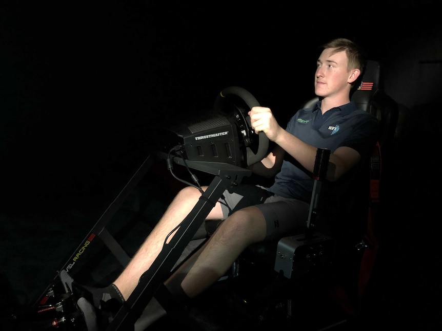 A teenage boy sits in a racing car simulator