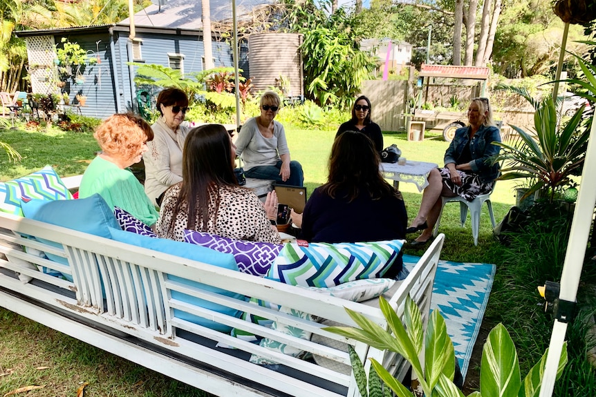 Group of artists sitting in sunny garden setting discussing starting a new arts hub 