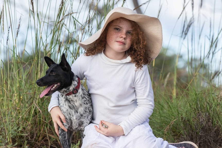 A shot from the film, a young girl sits with her dog