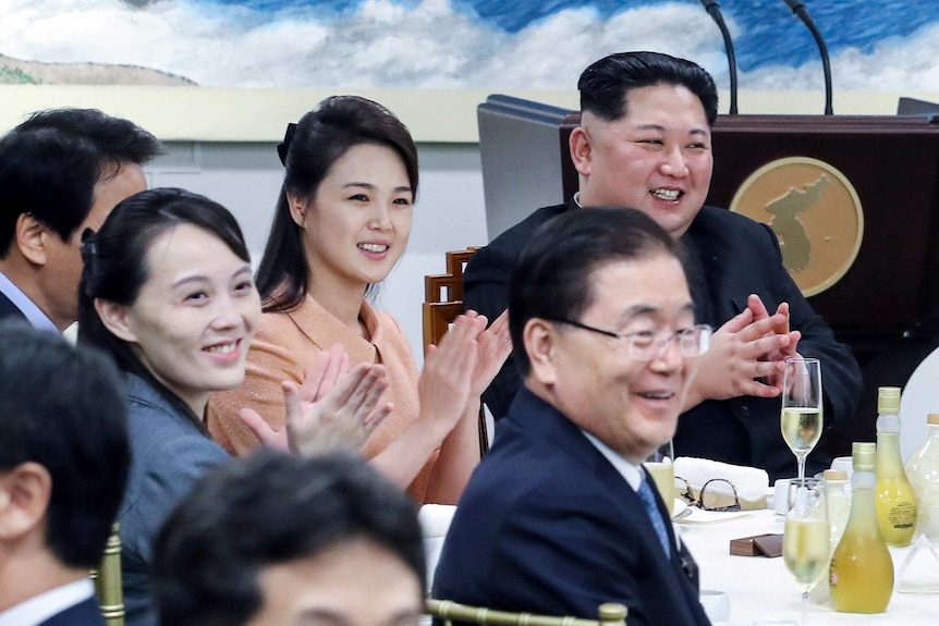 North Korean leader Kim Jong Un sits at a table and applauds at the South Korea summit