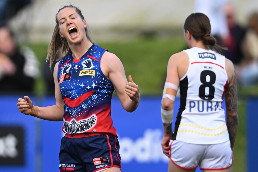 A Melbourne AFLW player pumps her fists as she celebrates a goal against St Kilda.