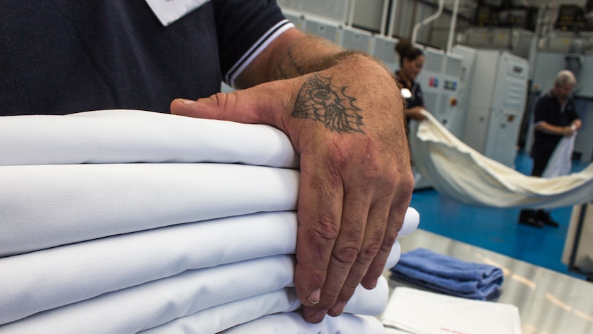 Hands carry folded linen at the Vanguard Laundry