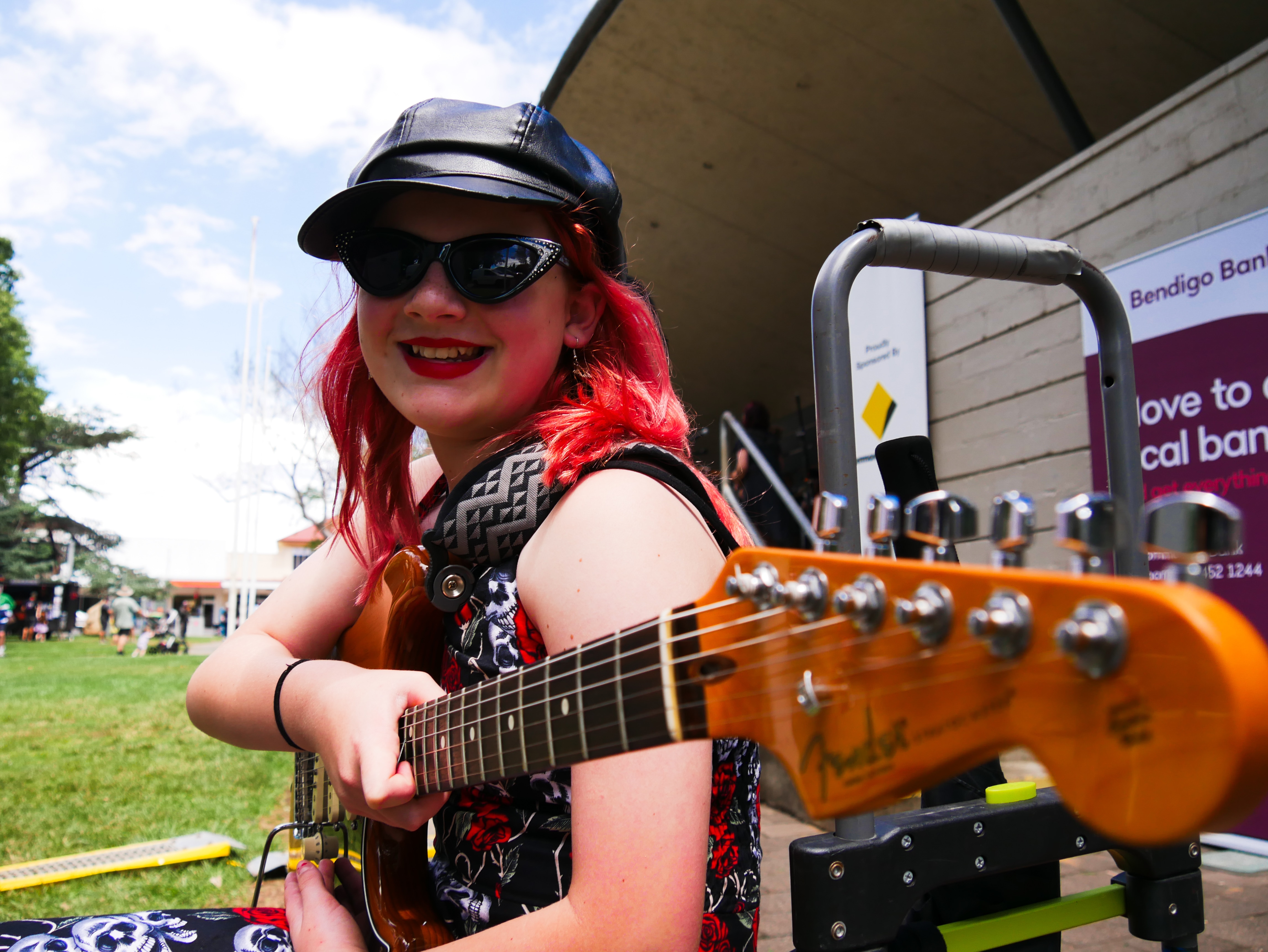 a kid smiles at the camera wearing cool sunnies and a guitar