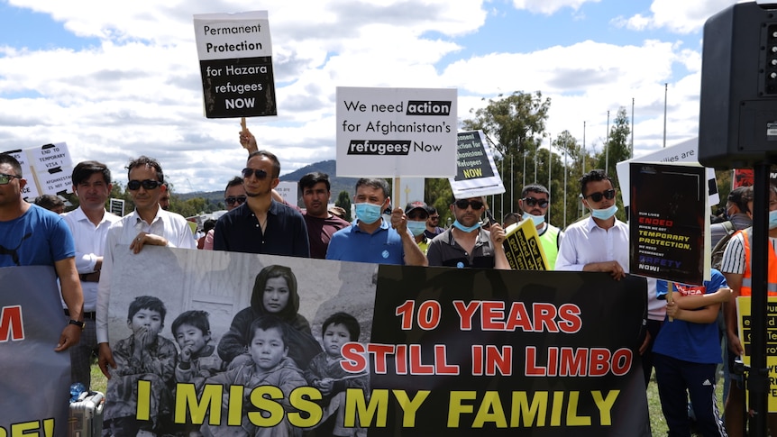 A group of Afghan refugees and asylum seekers hold up signs at a rally in front of Parliament House in Canberra.