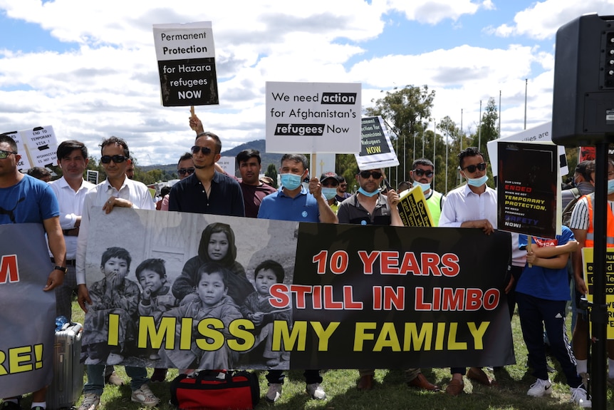 A group of Afghan refugees and asylum seekers hold up signs at a rally in front of Parliament House in Canberra.