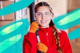 A woman wearing safety equipment holds a mop in a warehouse.