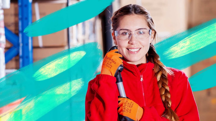 A woman wearing safety equipment holds a mop in a warehouse.