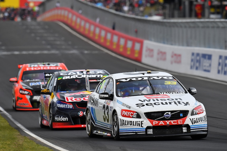 A Volvo driver leads the Bathurst 1000 ahead of two Holdens during a race, with all three close together.