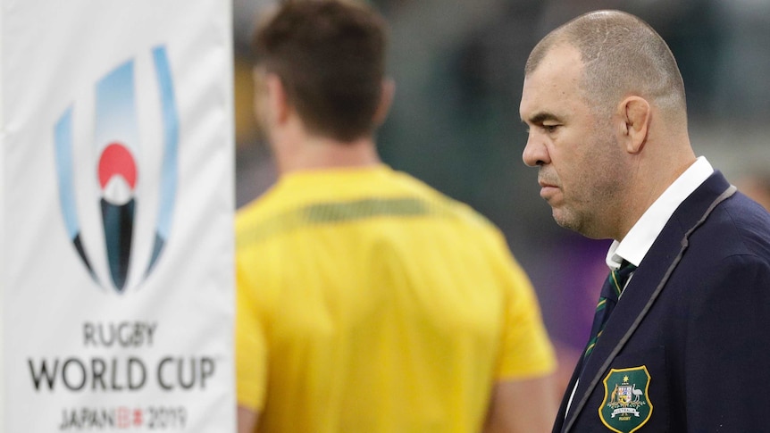 An Australian rugby union coach stands next to a goalpost before a Rugby World Cup quarterfinal.