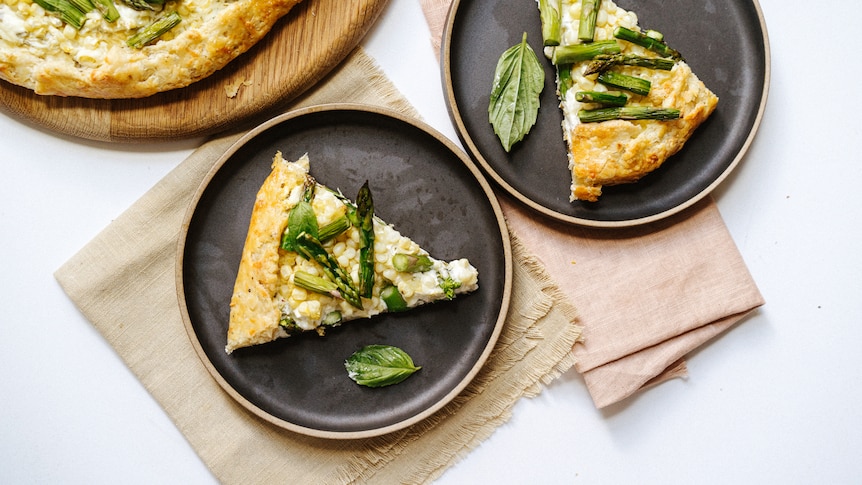 A spring onion, corn and asparagus galette sliced and plated, a vegetarian dinner or picnic idea.