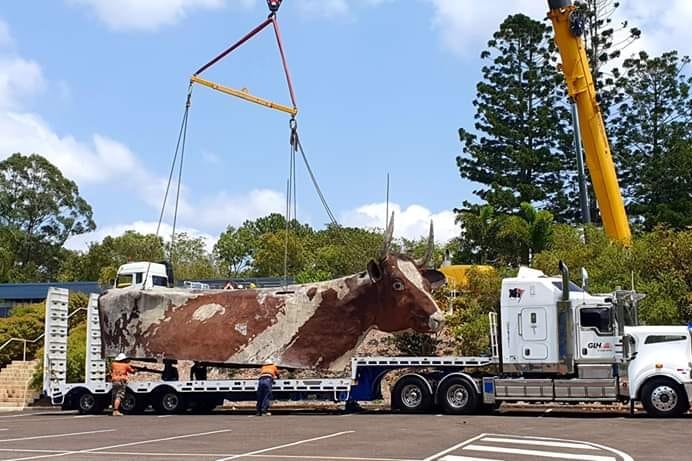 cow sculpture being loaded onto truck