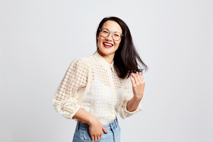 Portrait of comedian and writer Lizzy Hoo wearing a white blouse and jeans.