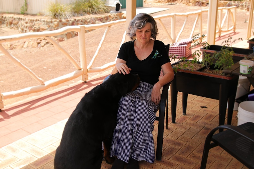 Myree sits on the porch with the dog, Max's head in her lap.