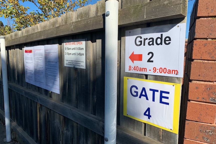 A fence with signs pointing Grade 2 students to the correct gate they can enter the school from.