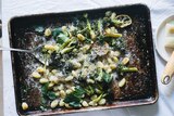 A baking tray with cooked gnocchi, broccoli topped with parsley and cheese, an easy vegetarian dinner recipe from Hetty McKinnon