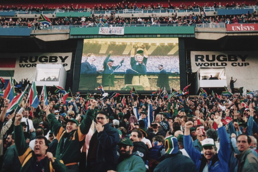 South African fans watch Springboks captain Francois Pienaar lift Rugby World Cup trophy in 1995.