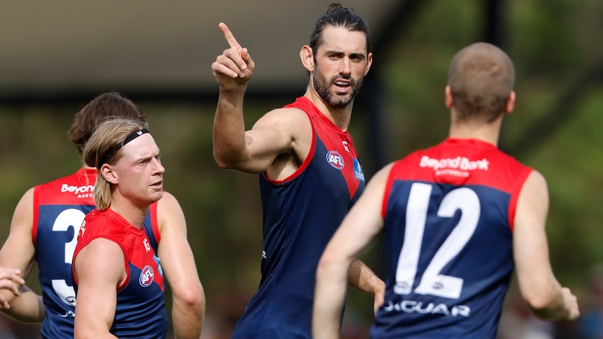 Melbourne ruck-forward Brodie Grundy points his finger in celebration after kicking a goal during a game.