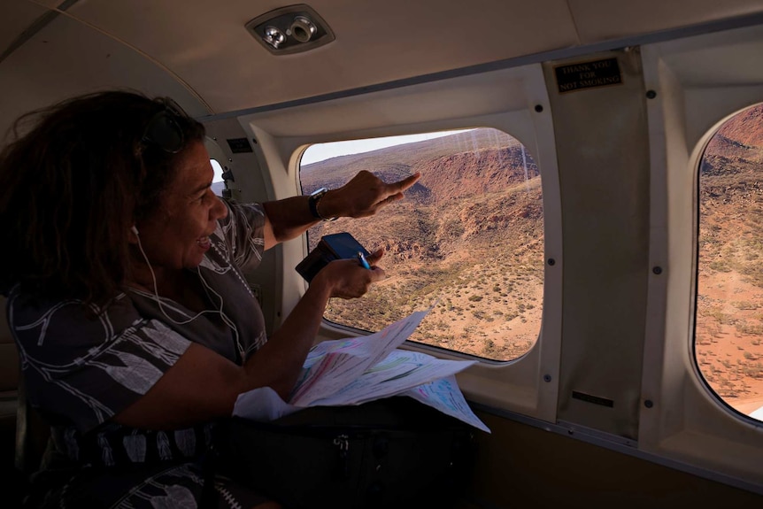 Leanne Liddle points out of the window of a plane.