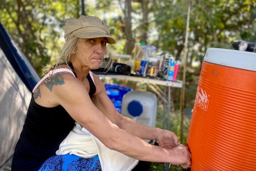 a woman in a cap pours from a large plastic urn