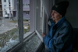 A woman wearing a black headbank and blue jumper stares out the window.