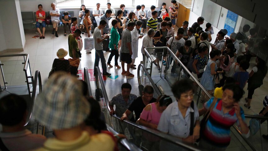 People ride on escalators as others queue at a hospital in Shanghai.