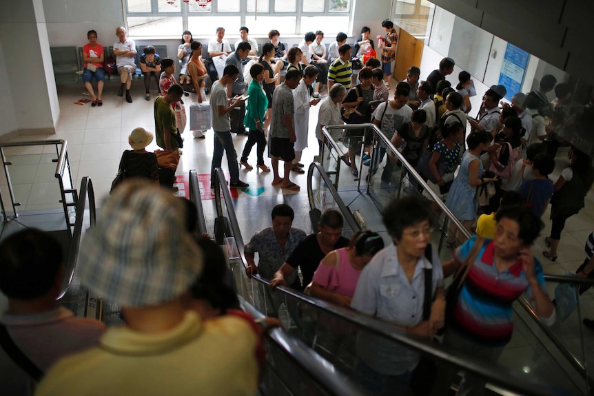 People ride on escalators as others queue at a hospital in Shanghai.