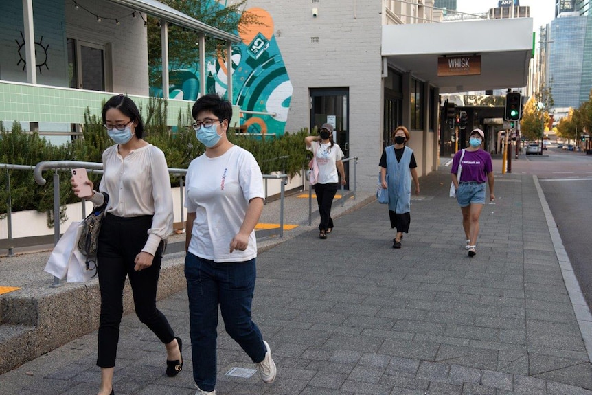 Five people walk along William Street in Perth during the daytime wearing face masks.