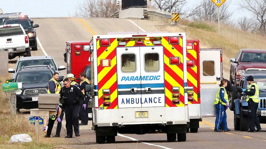 Emergency vehicle block a rural roadway, with police officers, firefighters and paramedics on the scene.
