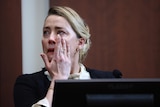 A woman in a courtroom wipes tears from her face