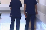 Two nurses stand in a hospital corridor.