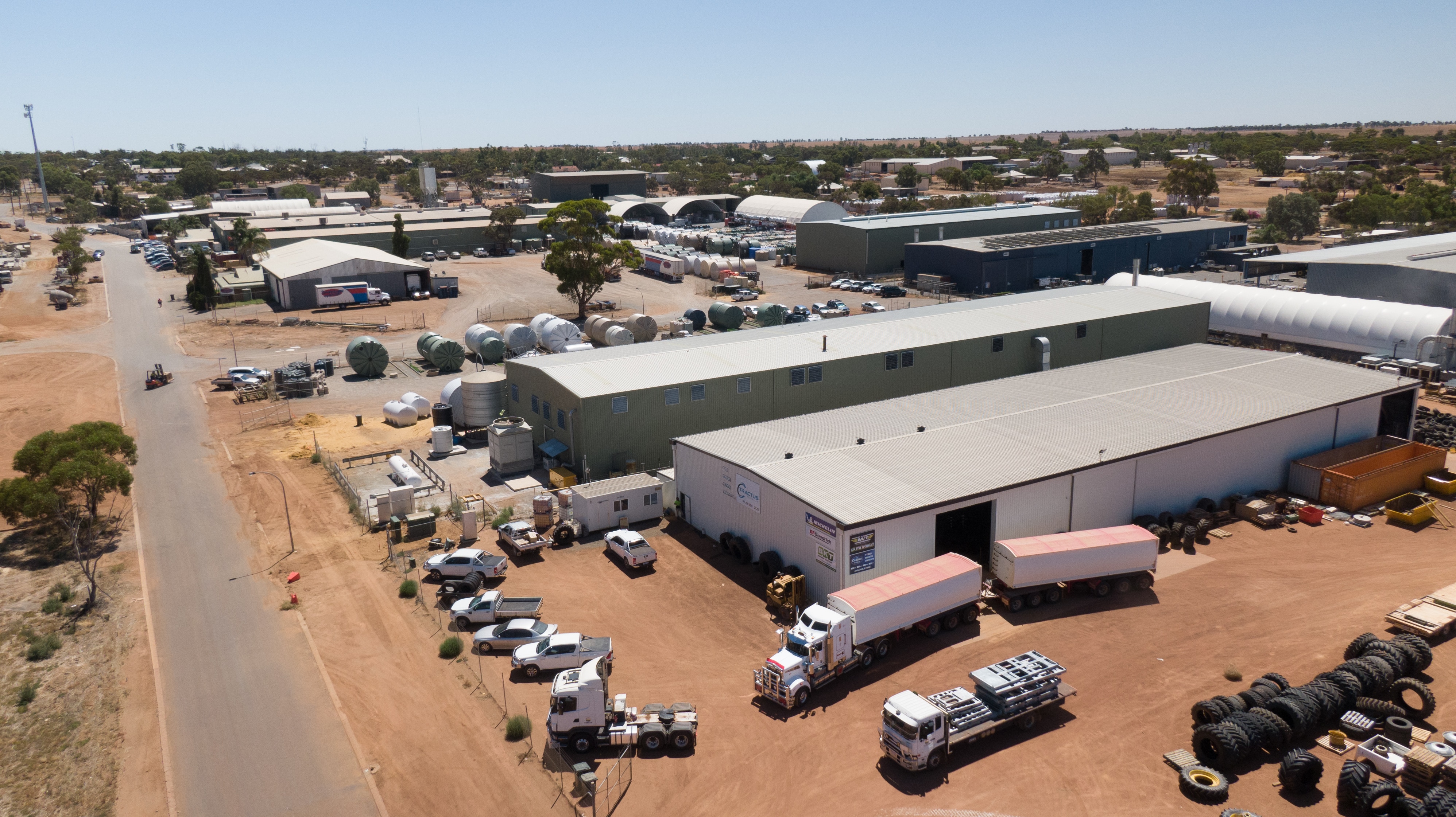 A drone photo of an industrial area with sheds, cars and trucks.
