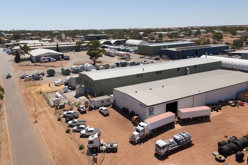 A drone photo of an industrial area with sheds, cars and trucks.