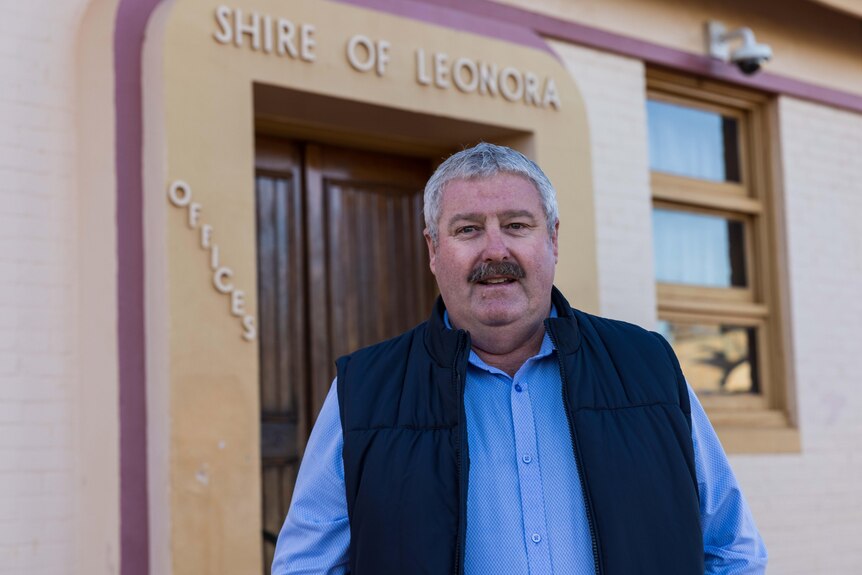 A man with grey hair who is shire president standing in front of a council administration building.  