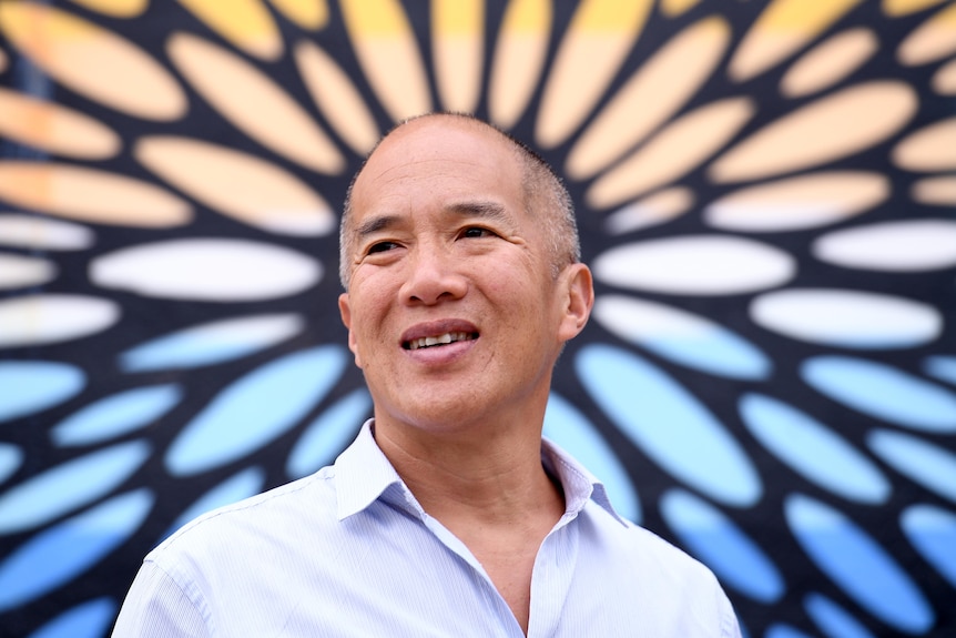 Picture of a smiling man against a brightly-coloured background. 