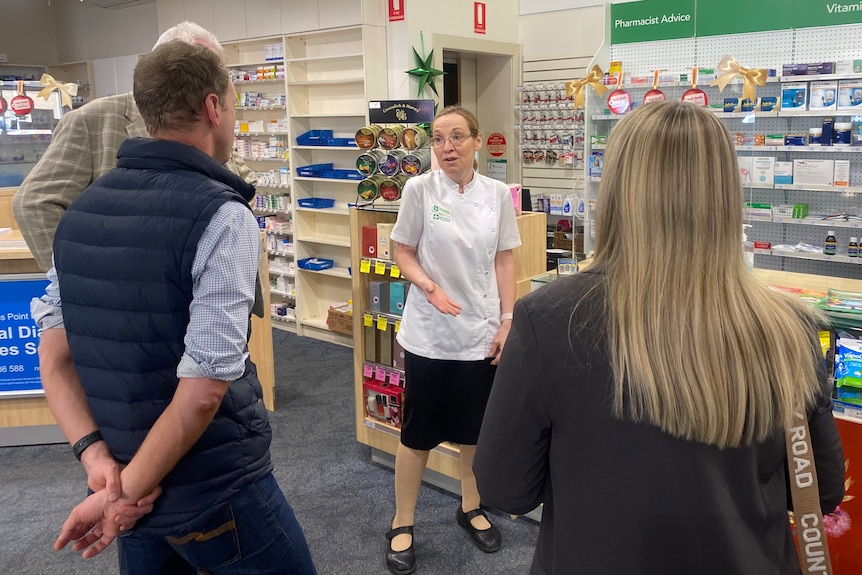 A woman speaks to other people in a pharmacy