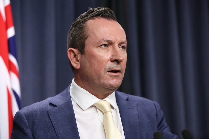 A head and shoulders shot of Mark McGowan speaking during a media conference indoors.