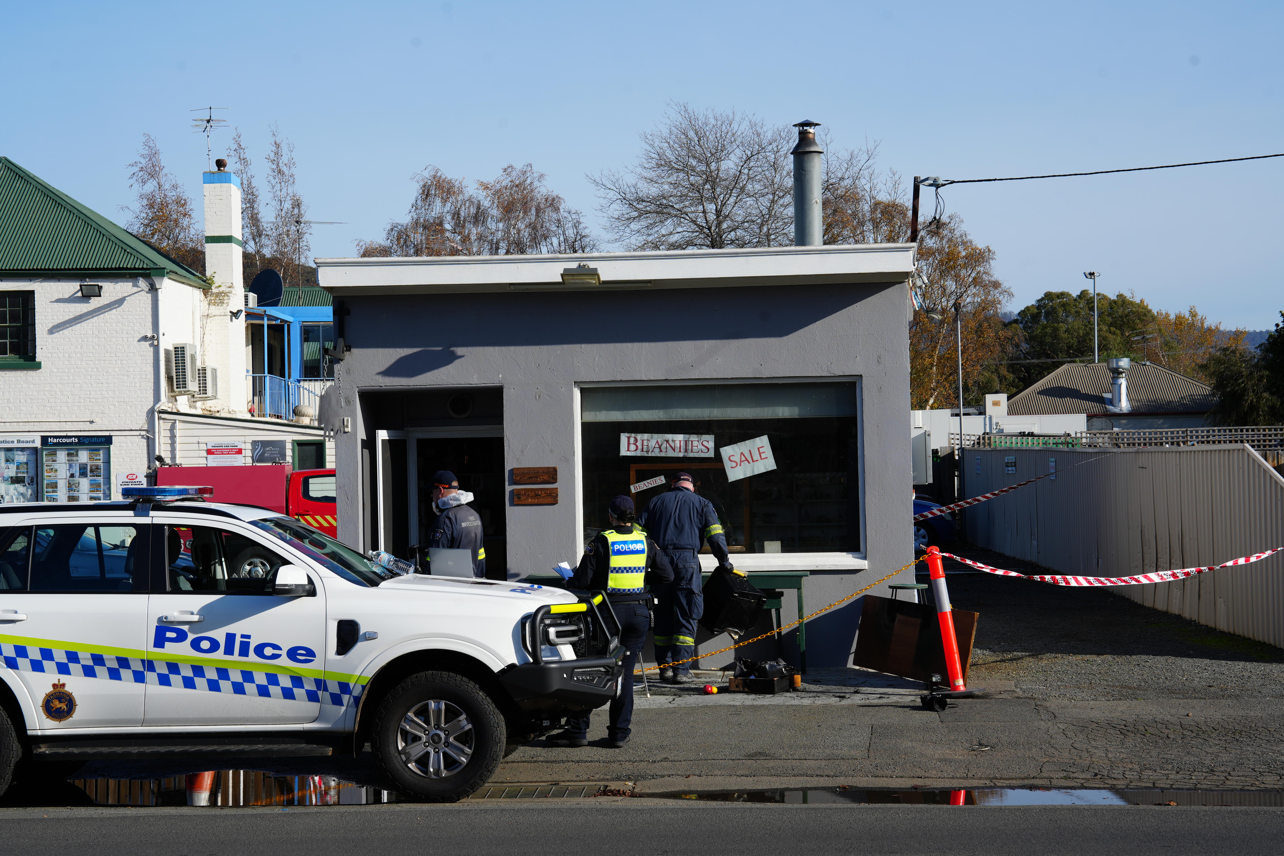 Tasmania Police vehicle and officer in front of a damaged building